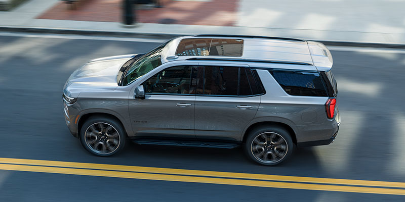 Silver Chevrolet Tahoe driving on a city street.