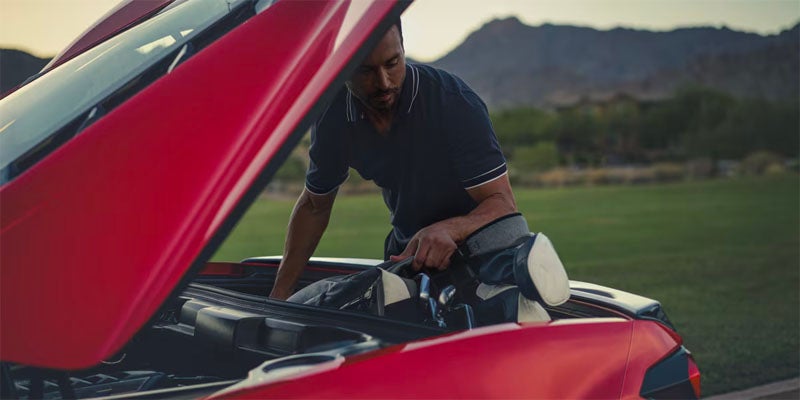 Man opening front trunk of Corvette