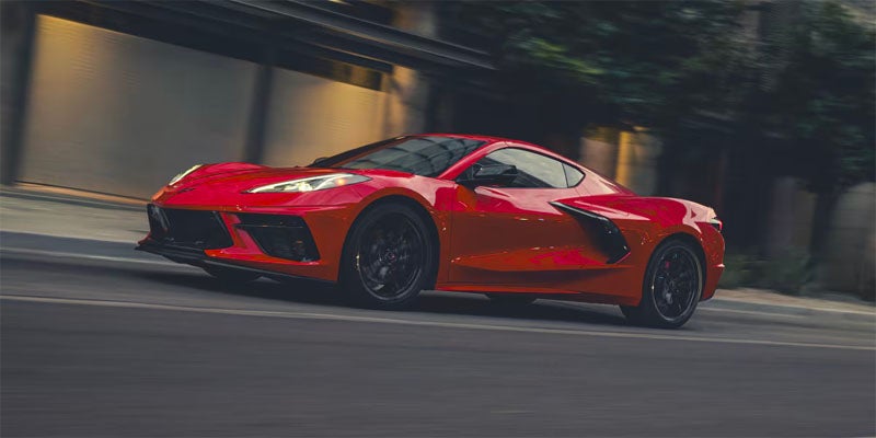 Red Corvette driving on city street
